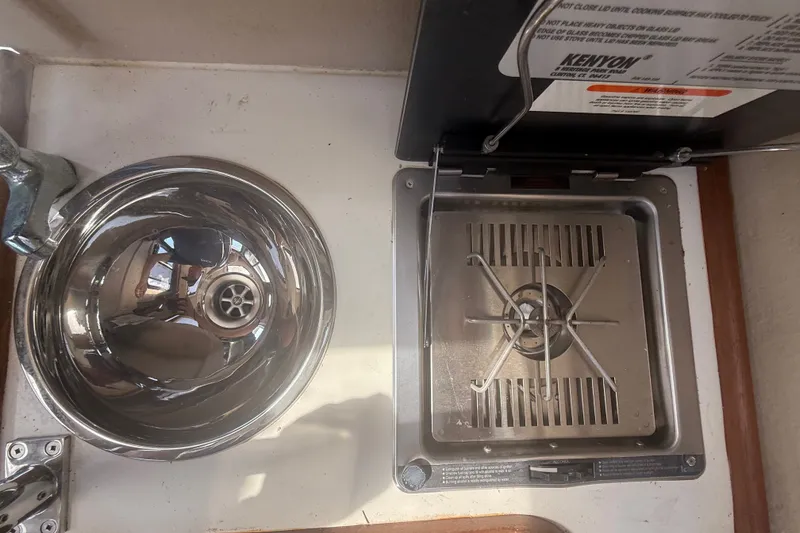 Slide: The Image of Compact kitchen area in a 2012 Ranger Tugs R-21 EC, featuring a stove and sink. - 28