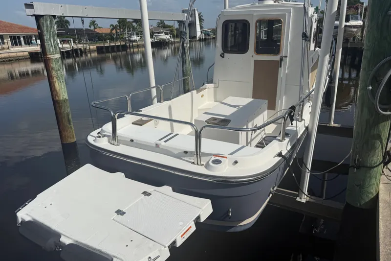 Slide: The Image of 2012 Ranger Tugs R-21 EC docked in a serene marina setting. - 50