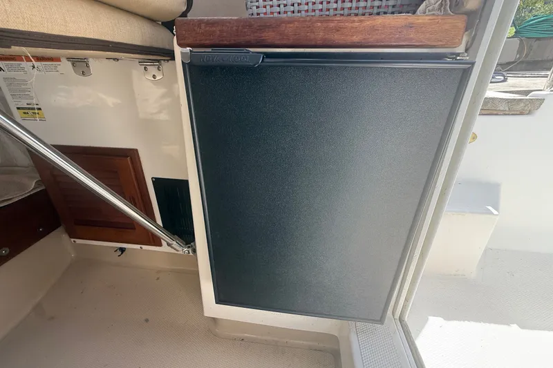 Slide: The Image of Interior view of a 2012 Ranger Tugs R-21 EC, featuring a compact refrigerator. - 29
