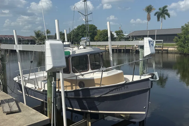 Slide: The Image of 2012 Ranger Tugs R-21 EC docked in a serene marina setting. - 1