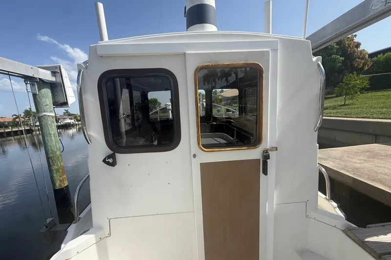 Slide: The Image of 2012 Ranger Tugs R-21 EC boat docked, rear view showing cabin and windows. - 9