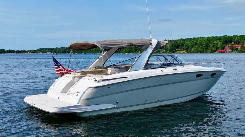 Slide: The Image of 2012 Regal 3550 Cuddy on calm water with a sunshade and American flag. - 5