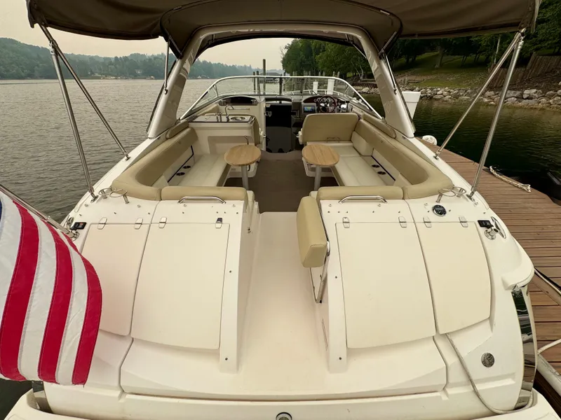Slide: The Image of 2012 Regal 3550 Cuddy: Spacious cockpit with beige seating, table, and canopy, docked by the shore. - 16