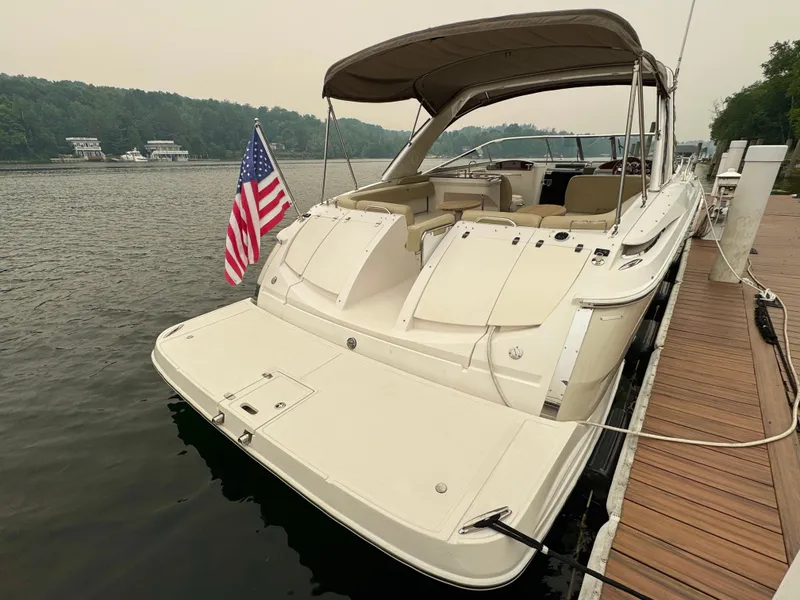 Slide: The Image of 2012 Regal 3550 Cuddy at dock with US flag, spacious deck, and covered seating area. - 15