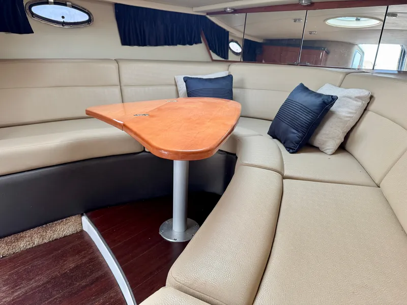 Slide: The Image of Interior of the 2012 Regal 3550 Cuddy with beige sofa and wooden table. - 2