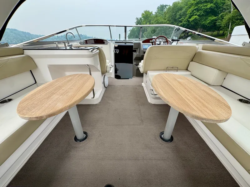Slide: The Image of Interior of a 2012 Regal 3550 Cuddy with two wooden tables and beige seating. - 20