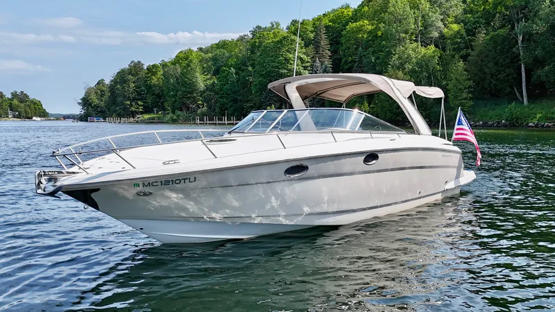 The Image of 2012 Regal 3550 Cuddy on calm water, surrounded by green trees, with a US flag. - 0