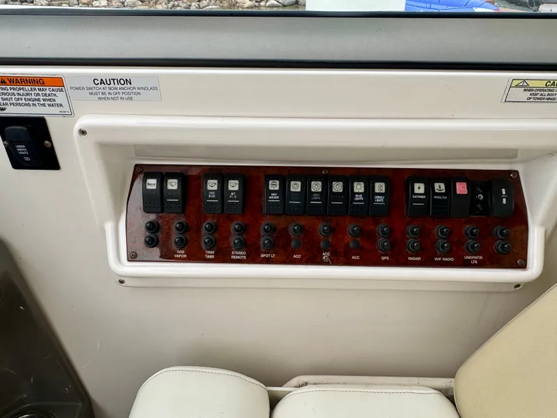 Slide: The Image of Control panel of a 2012 Regal 3550 Cuddy boat with various switches and warning labels. - 29