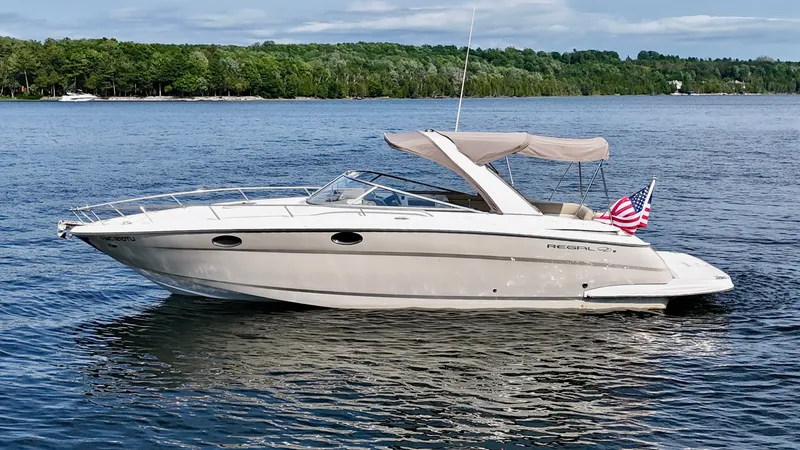 Slide: The Image of 2012 Regal 3550 Cuddy on a calm lake with a wooded shoreline in the background. - 3