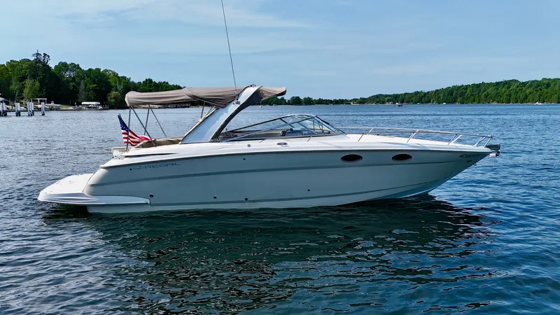 Slide: The Image of 2012 Regal 3550 Cuddy on calm water with a bimini top and American flag. - 6