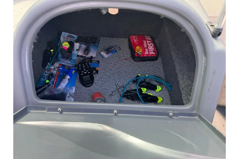 Slide: The Image of Storage compartment in a 2011 Lund 1625 Rebel XL Sport boat with fishing gear and first aid kit. - 14
