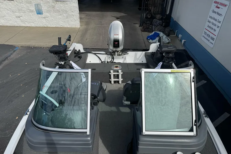 Slide: The Image of 2011 Lund 1625 Rebel XL Sport boat with windshield and motor, parked outside a marine store. - 12