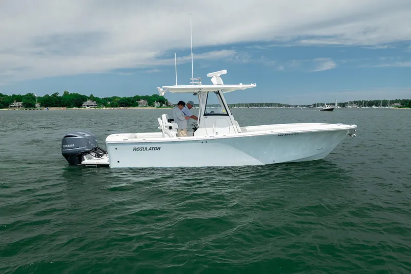 Slide: The Image of 2021 Regulator 28 Forward Seating boat on calm water with scenic shoreline background. - 6