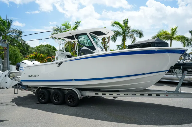 Slide: The Image of 2019 Blackfin 272 CC boat on trailer, surrounded by palm trees under a blue sky. - 5