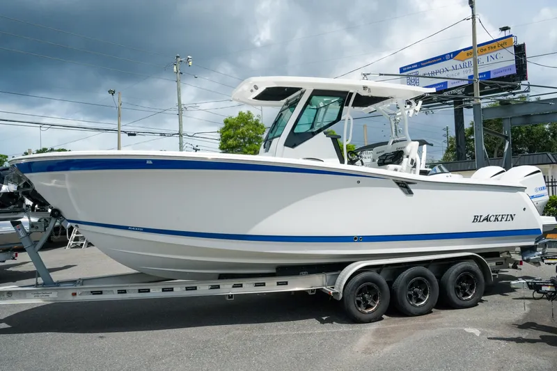 Slide: The Image of 2019 Blackfin 272 CC boat on trailer, displayed outdoors under cloudy sky. - 2