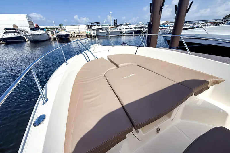 Slide: The Image of 2023 White Shark 230CC boat with cushioned seating, docked at a marina. - 2