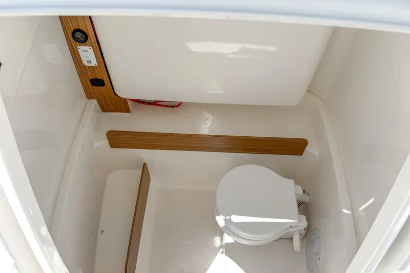 Slide: The Image of 2023 White Shark 230CC boat interior with compact marine toilet and wooden accents. - 7