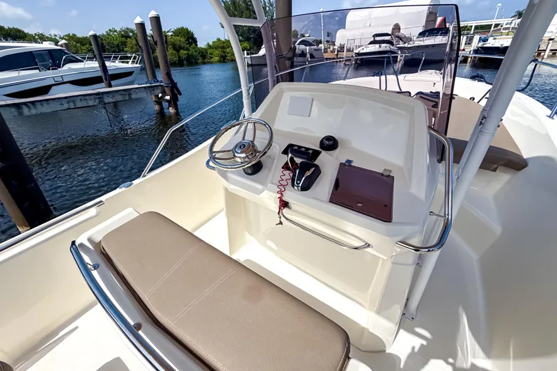 Slide: The Image of 2023 White Shark 230CC boat interior with steering console and seating at marina. - 9