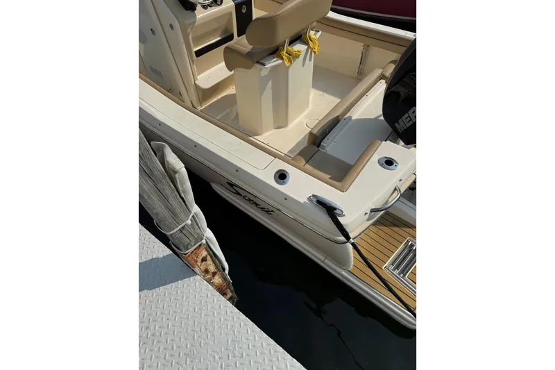 Slide: The Image of 2017 Scout 215 XSF boat docked, featuring beige seating and a Mercury engine. - 13