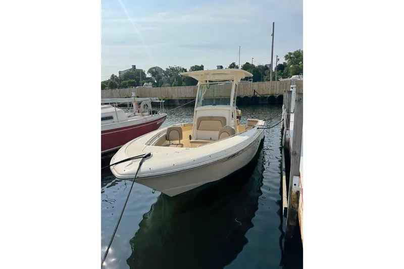 Slide: The Image of 2017 Scout 215 XSF boat docked in a marina under clear skies. - 2