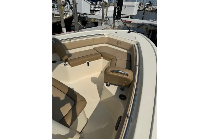 Slide: The Image of 2017 Scout 215 XSF boat interior with tan seating at a marina. - 8