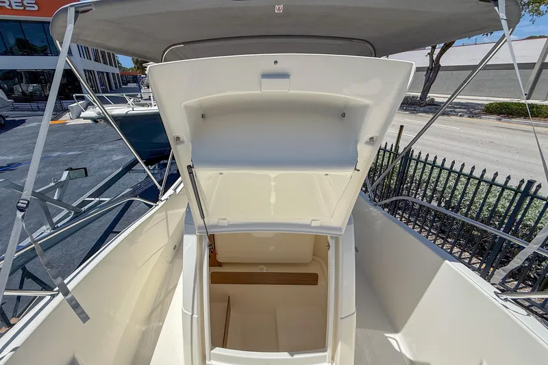 Slide: The Image of 2023 White Shark 210CC boat with open storage compartment, outdoor setting. - 4