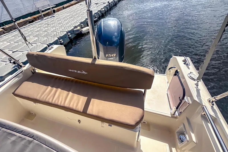 Slide: The Image of 2023 White Shark 210CC boat with cushioned seating and outboard motor at dock. - 7