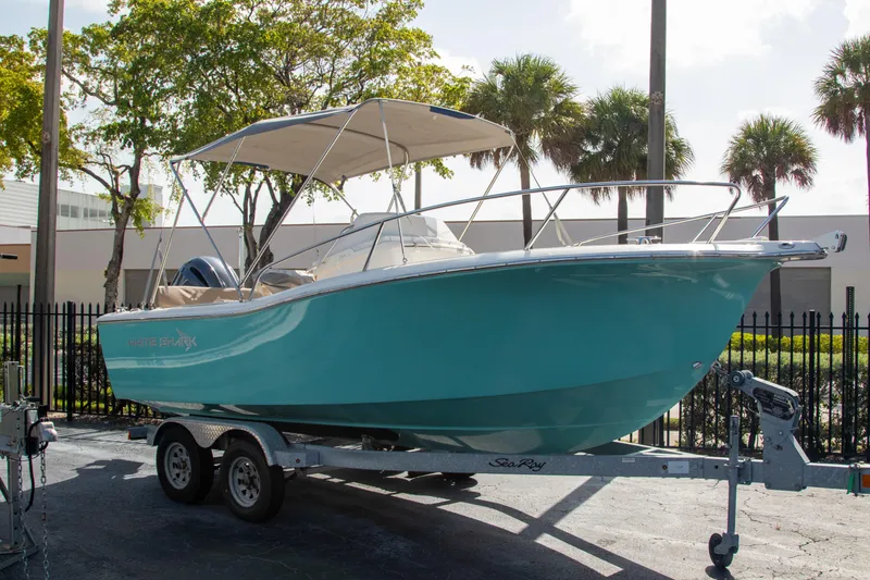 Slide: The Image of 2023 White Shark 210CC boat on trailer, turquoise hull, parked outdoors. - 1