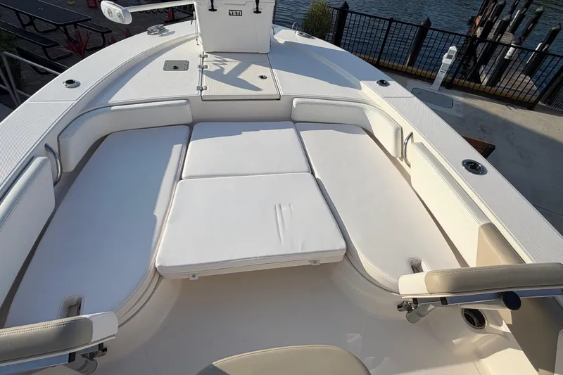 Slide: The Image of 2018 Robalo 246 Cayman boat interior with cushioned seating and rod holders by the water. - 17