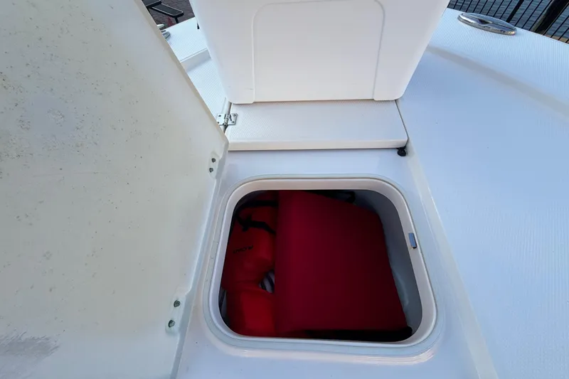 Slide: The Image of Open storage compartment on 2018 Robalo 246 Cayman boat with red life jacket inside. - 14