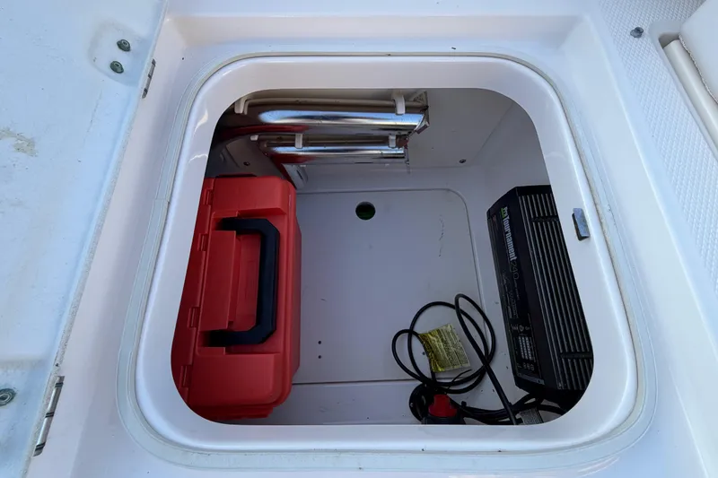 Slide: The Image of Storage compartment of a 2018 Robalo 246 Cayman boat with red toolbox and battery charger. - 15