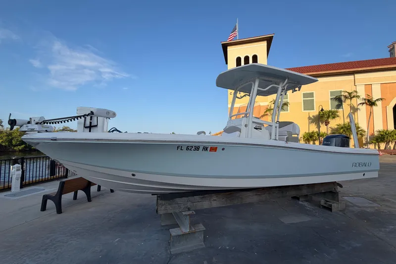 Slide: The Image of 2018 Robalo 246 Cayman boat displayed outdoors near a building with palm trees. - 1