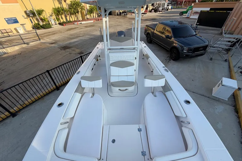 Slide: The Image of 2018 Robalo 246 Cayman boat interior with seating and console, parked near a black truck. - 11