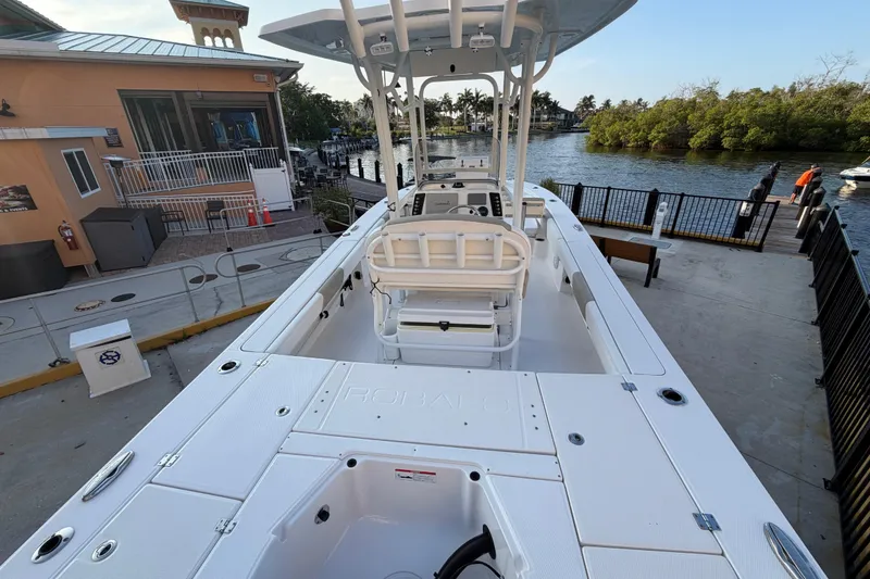 Slide: The Image of 2018 Robalo 246 Cayman boat docked near waterfront building and lush greenery. - 22