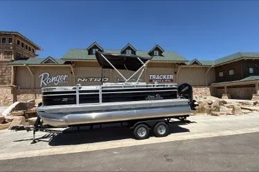 The Image of 2026 Sun Tracker SportFish 20 DLX pontoon boat on trailer, parked outdoors. - 0