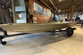 The Image of 2026 Tracker Grizzly 14 Jon boat displayed indoors on a trailer. - 0