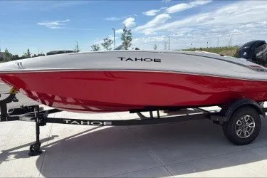 The Image of 2026 Tahoe T16 boat with red hull on trailer, parked outdoors under blue sky. - 0