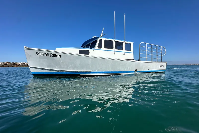 Slide: The Image of 2016 Libby Downeast boat "Coastal Reign" on calm water under clear blue sky. - 1