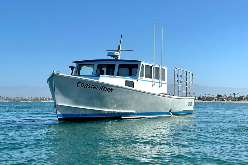 Slide: The Image of A 2016 Libby Downeast boat named "Coastal Reign" on calm blue waters. - 2