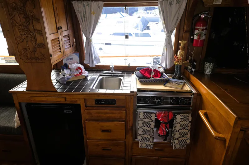 Slide: The Image of 1978 CHB 34 Trawler kitchen with wooden cabinets, sink, stove, and nautical decor. - 6
