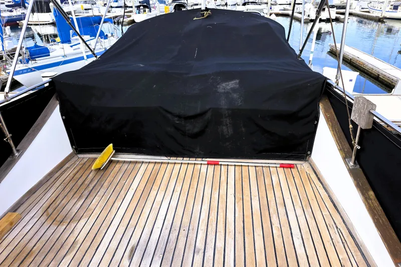 Slide: The Image of 1978 CHB 34 Trawler deck with black cover and wooden flooring at marina. - 27