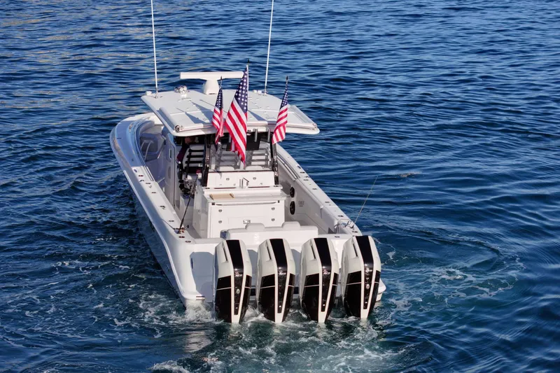 Slide: The Image of A luxury motorboat with four outboard engines cruises on calm water. Two American flags are flying. - 7