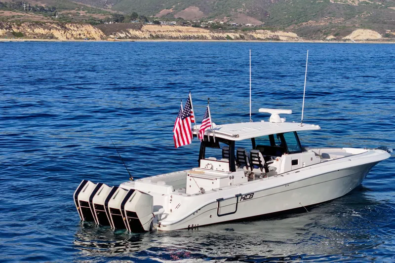 Slide: The Image of A 2026 HCB 42 Lujo on calm waters with four outboard engines and American flags. - 2