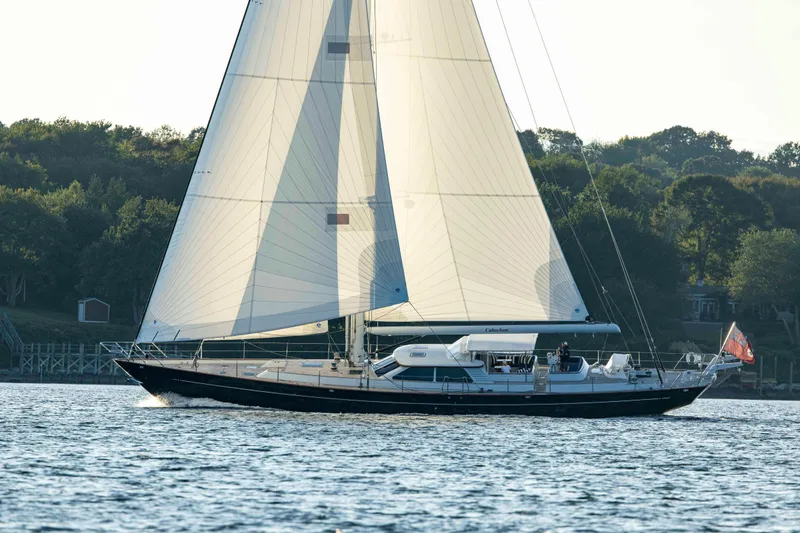 The Image of 2004 Ta Chiao Custom Pilothouse Cutter sailing on calm waters near a wooded shoreline. - 0