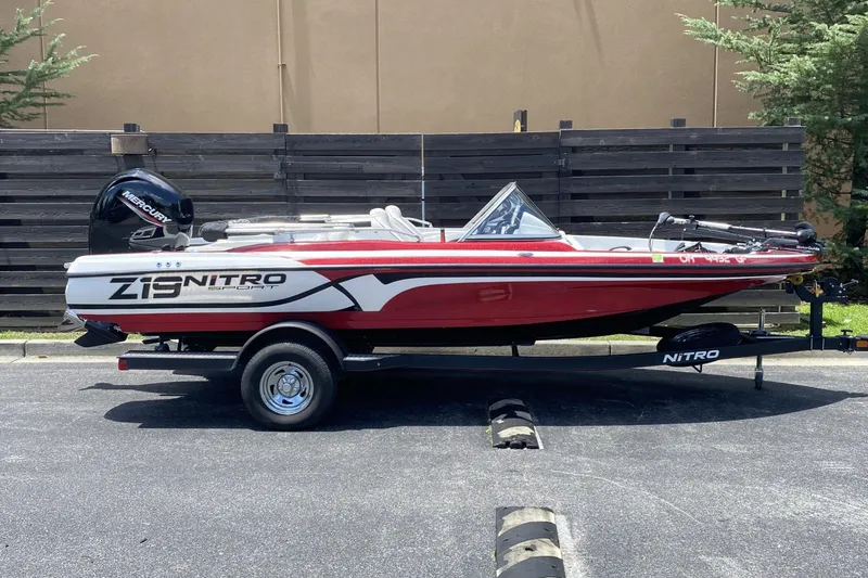 The Image of 2021 Nitro Z19 Sport boat on trailer, red and white design, parked outdoors. - 0
