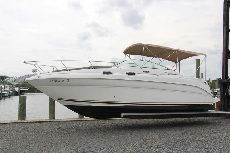 Slide: The Image of 2002 Sea Ray Sundancer 260 boat docked, featuring sleek design and beige canopy. - 2