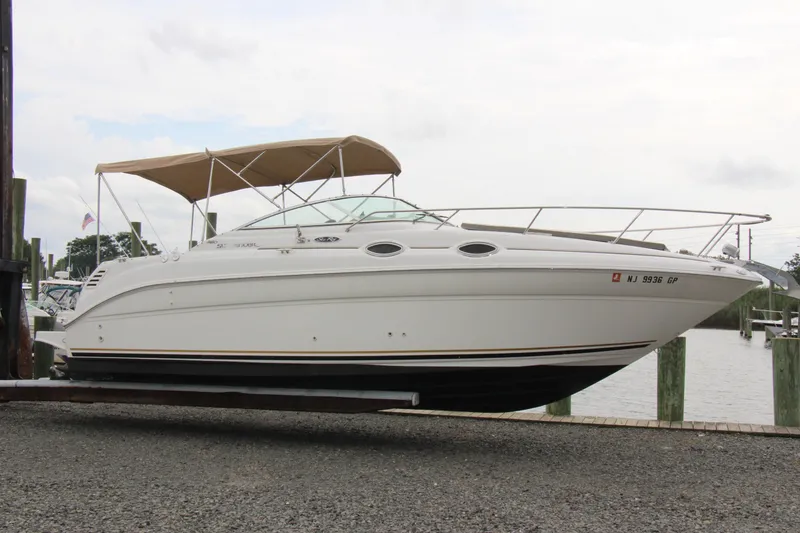 Slide: The Image of 2002 Sea Ray Sundancer 260 boat docked, featuring sleek design and beige canopy. - 3