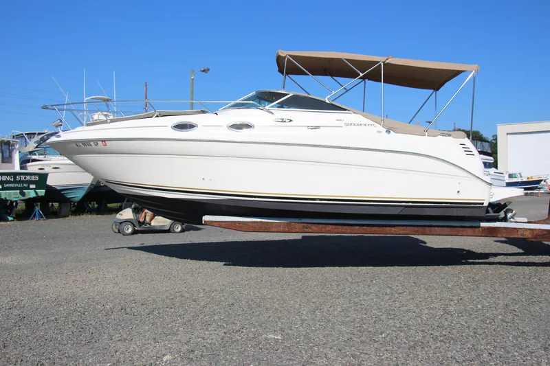 Slide: The Image of 2002 Sea Ray Sundancer 260 boat on trailer, displayed outdoors under clear blue sky. - 0