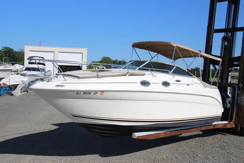 Slide: The Image of 2002 Sea Ray Sundancer 260 boat with canopy, displayed on a forklift in a marina. - 1