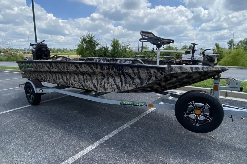 Slide: The Image of 2022 Havoc 1860 DBST camo boat on trailer in parking lot under cloudy sky. - 2
